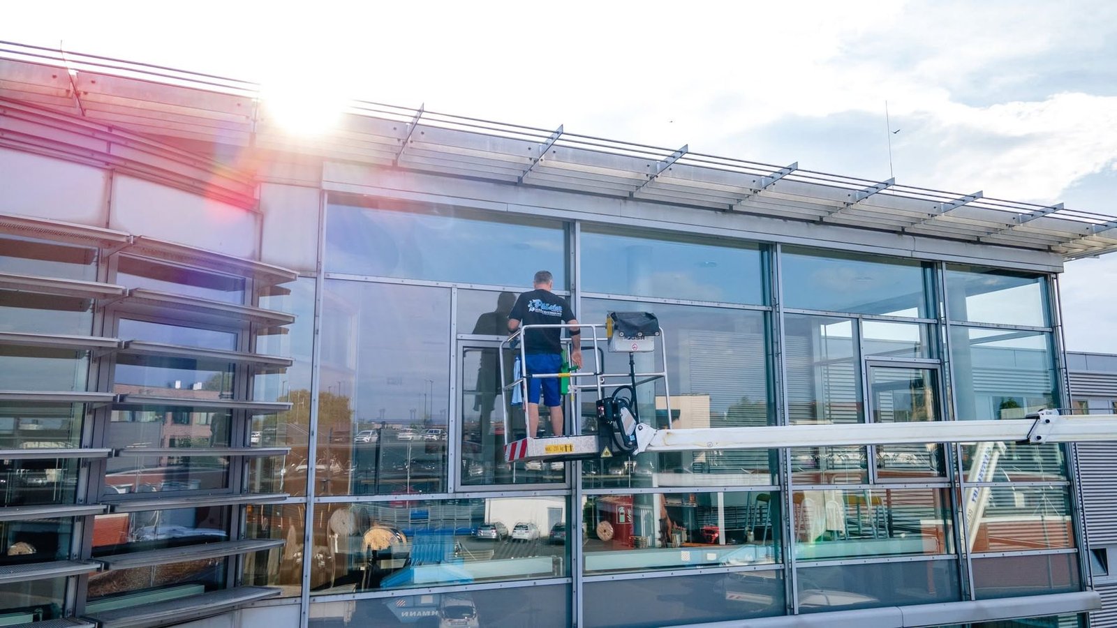 Pläster Mitarbeiter reinigt eine Glasfassade von der Hubarbeitsbühne aus